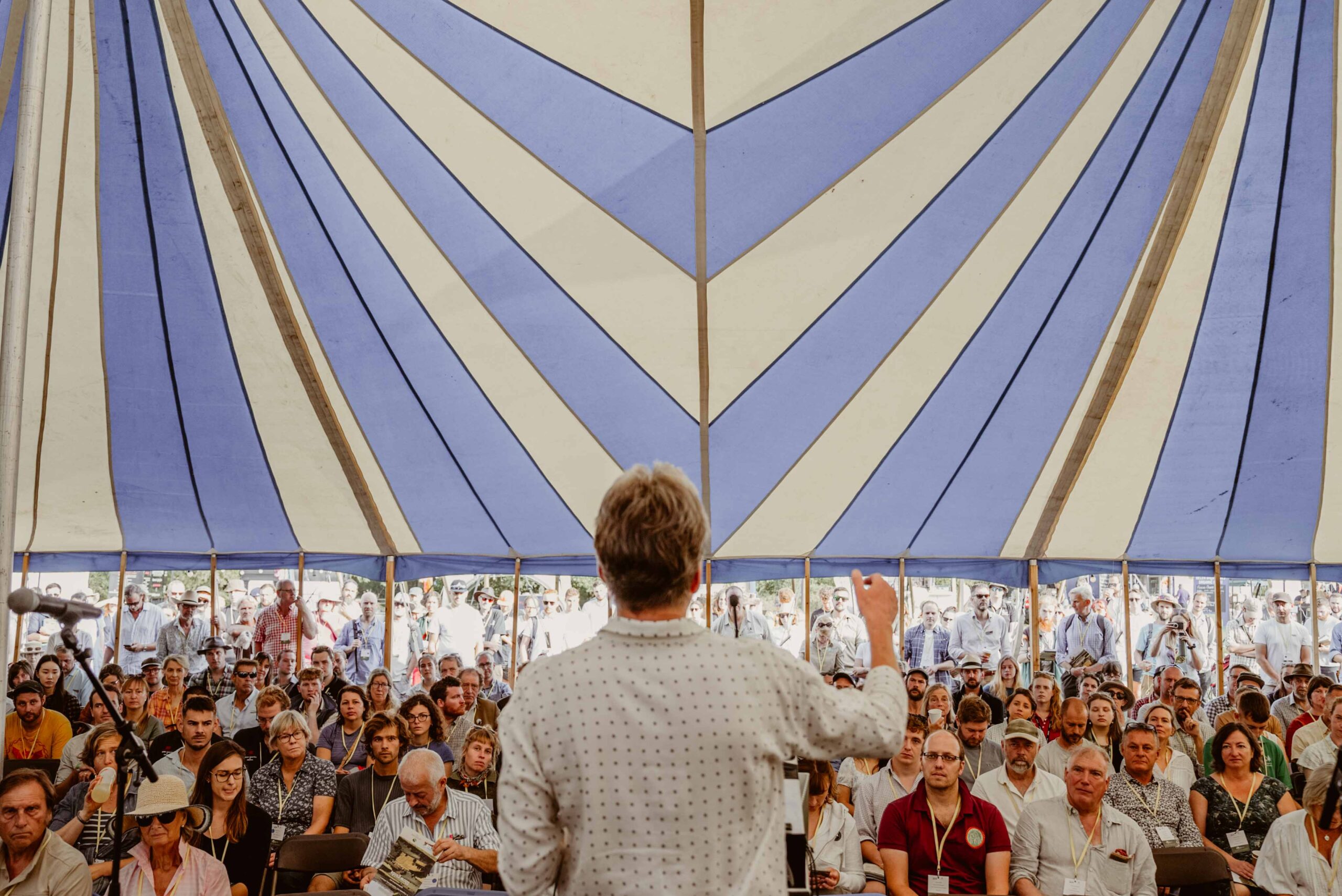 Speaker presents to a crowd under a bell tent
